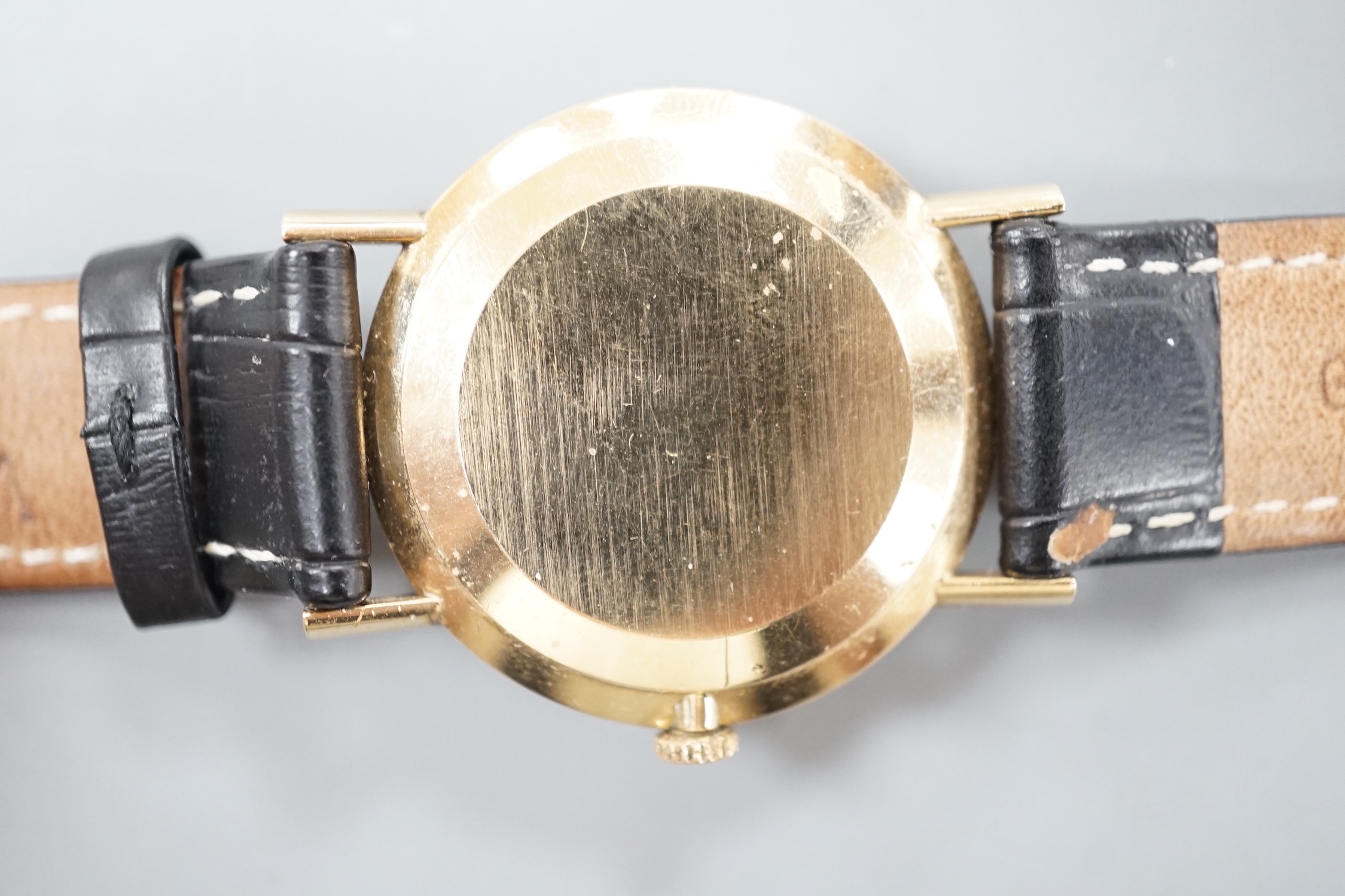 A gentleman's 9ct gold Omega manual wind wrist watch, with date aperture, on a black leather Omega strap with Omega buckle, cased diameter 33mm